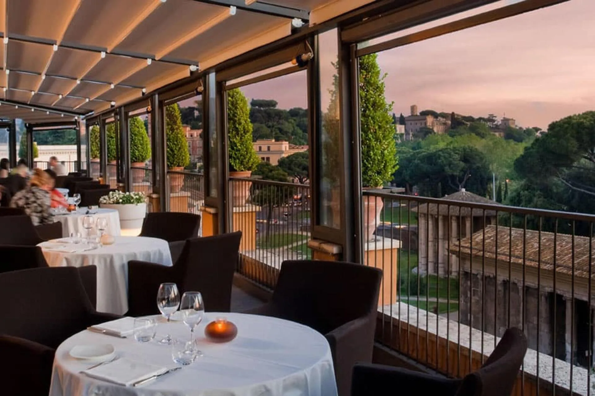 Terraza de alta gastronomía al anochecer con vistas a Roma